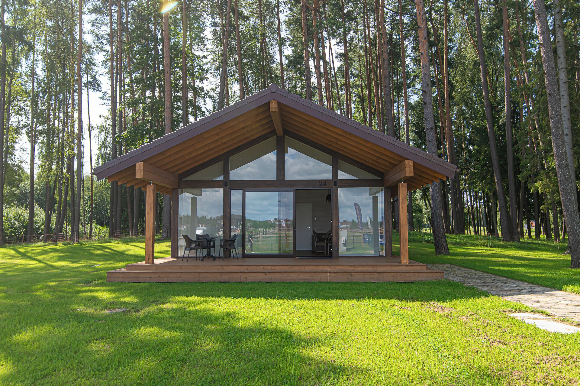 Une cabane en bois avec une façade en verre, entourée d’une forêt.