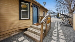 A wooden house with a blue door, a satellite dish, and a gravel driveway.