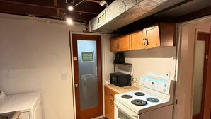 A compact kitchen with a white stove, a microwave, wooden cabinets, and a small refrigerator.