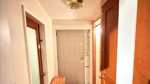 A narrow hallway with wooden flooring, white walls, and a white door at the end.