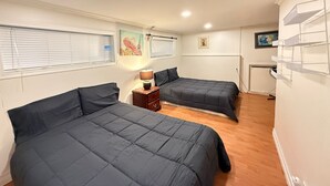 A bedroom with two beds, a nightstand, and a lamp.