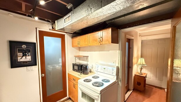A compact kitchen with a stove, microwave, and wooden cabinets.
