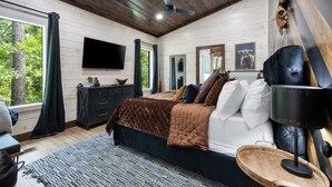 Une chambre à coucher avec un grand lit, une télévision, un ventilateur de plafond et une tête de lit en bois.