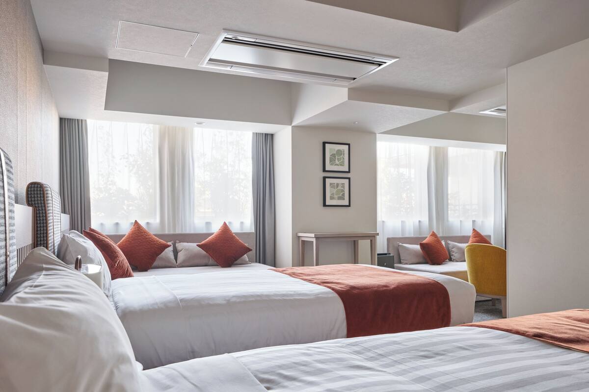 A hotel room with two beds, a desk, and a chair.
