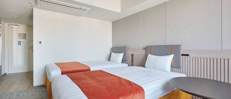 A hotel room with two beds, a round table, and a built-in bench.