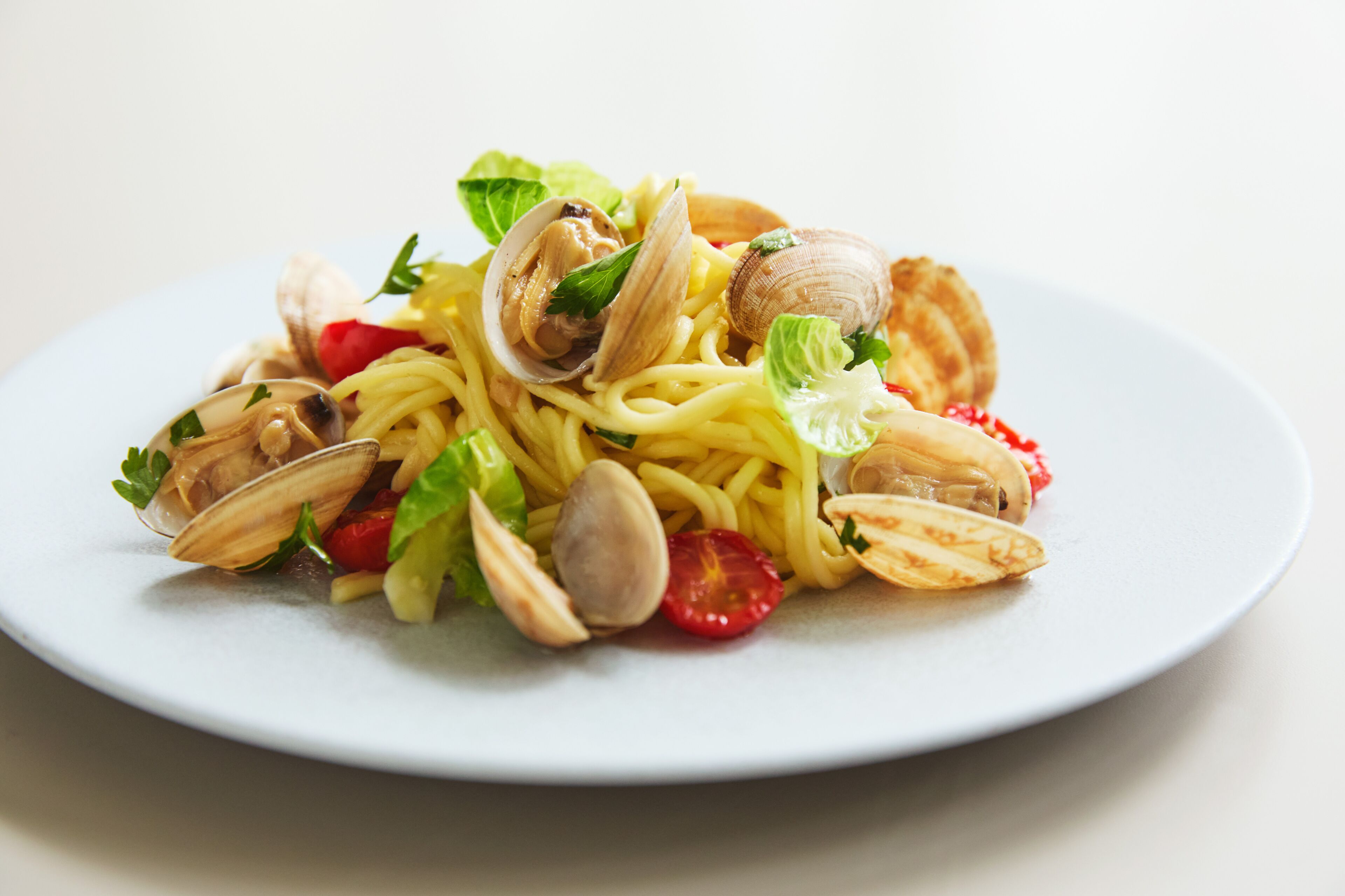 A plate of spaghetti with clams and cherry tomatoes.
