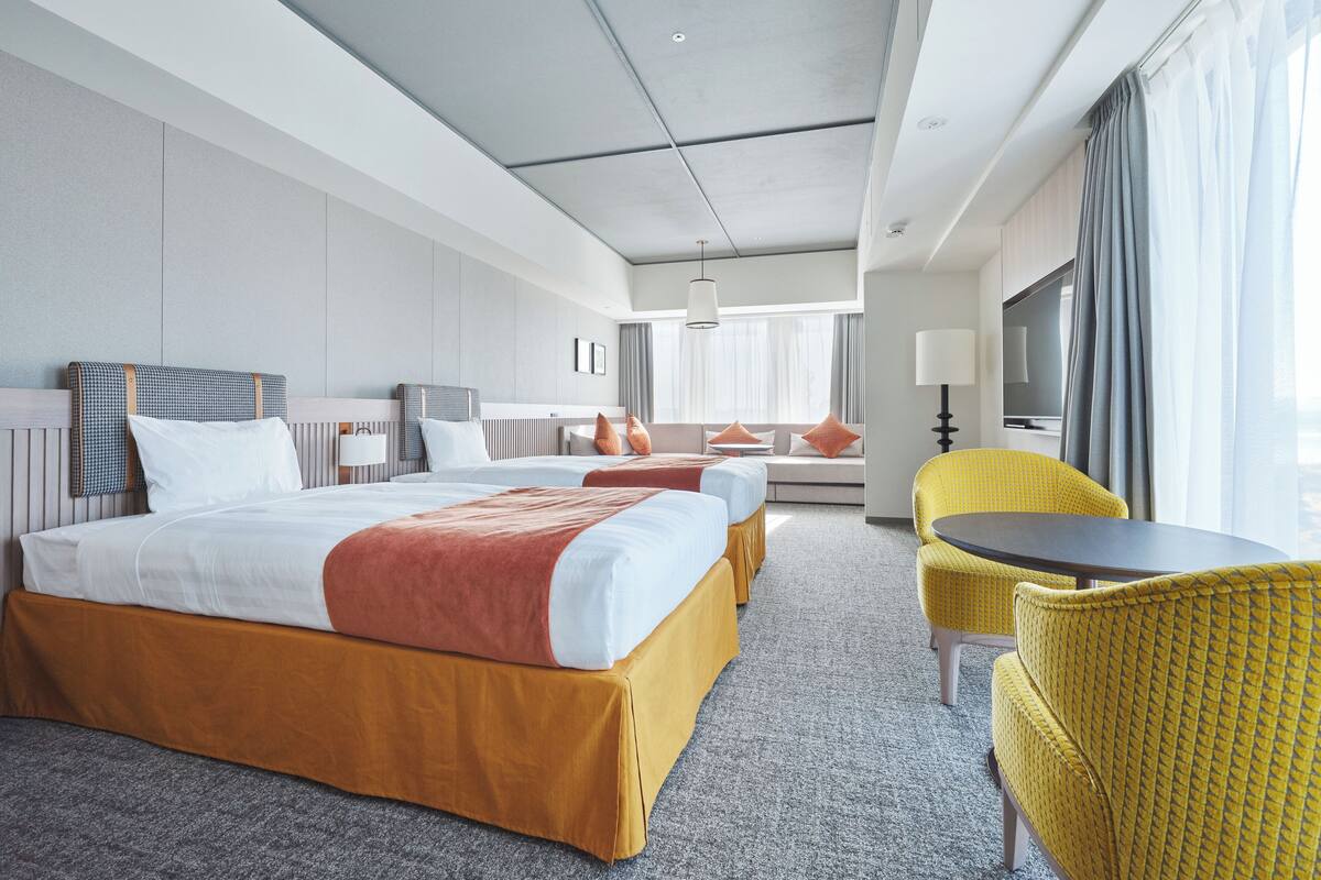 A hotel room with a large bed, a sofa, a small table, and a TV.