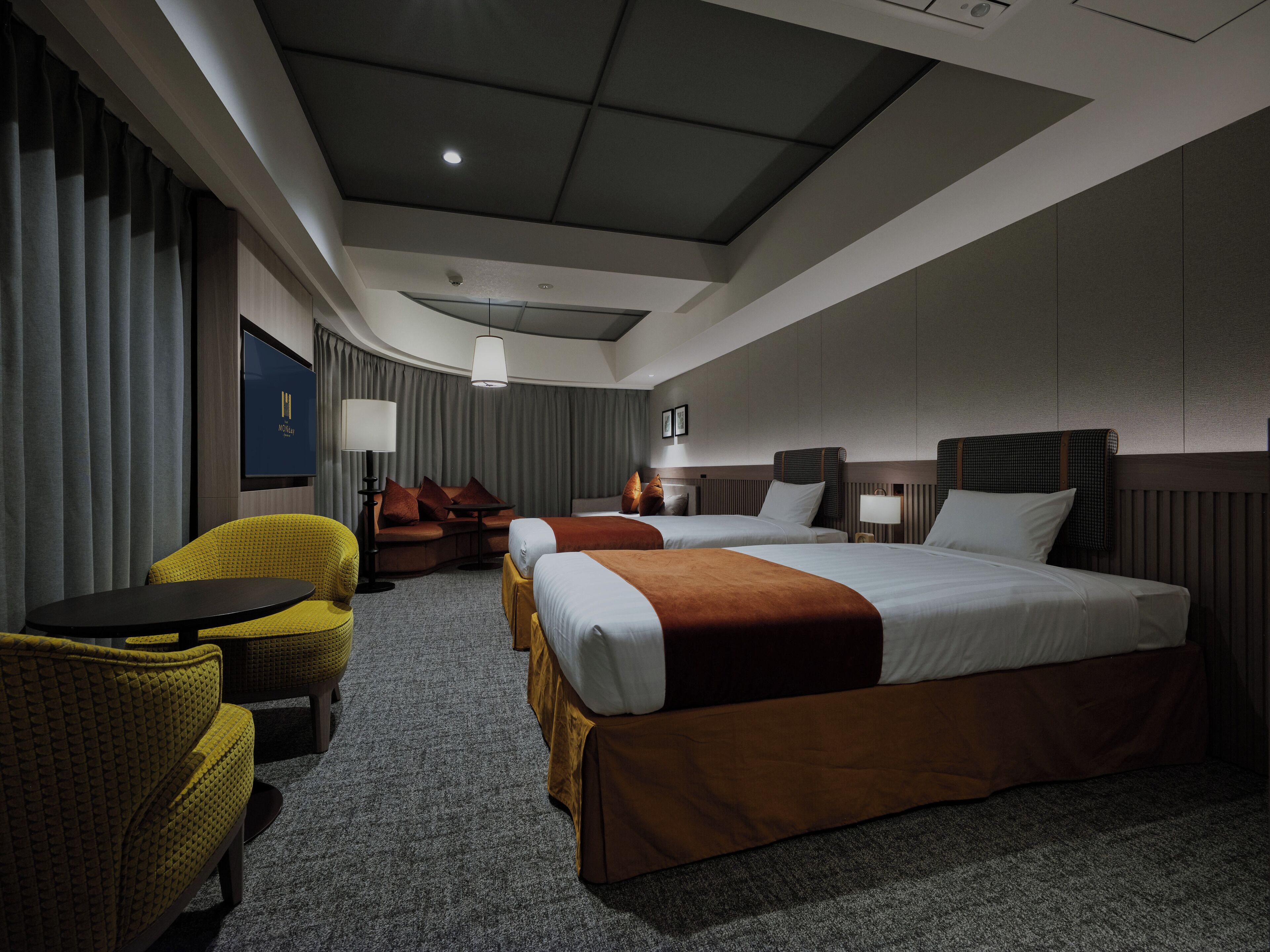 A hotel room with a large bed, a sofa, a small table, and a chair.
