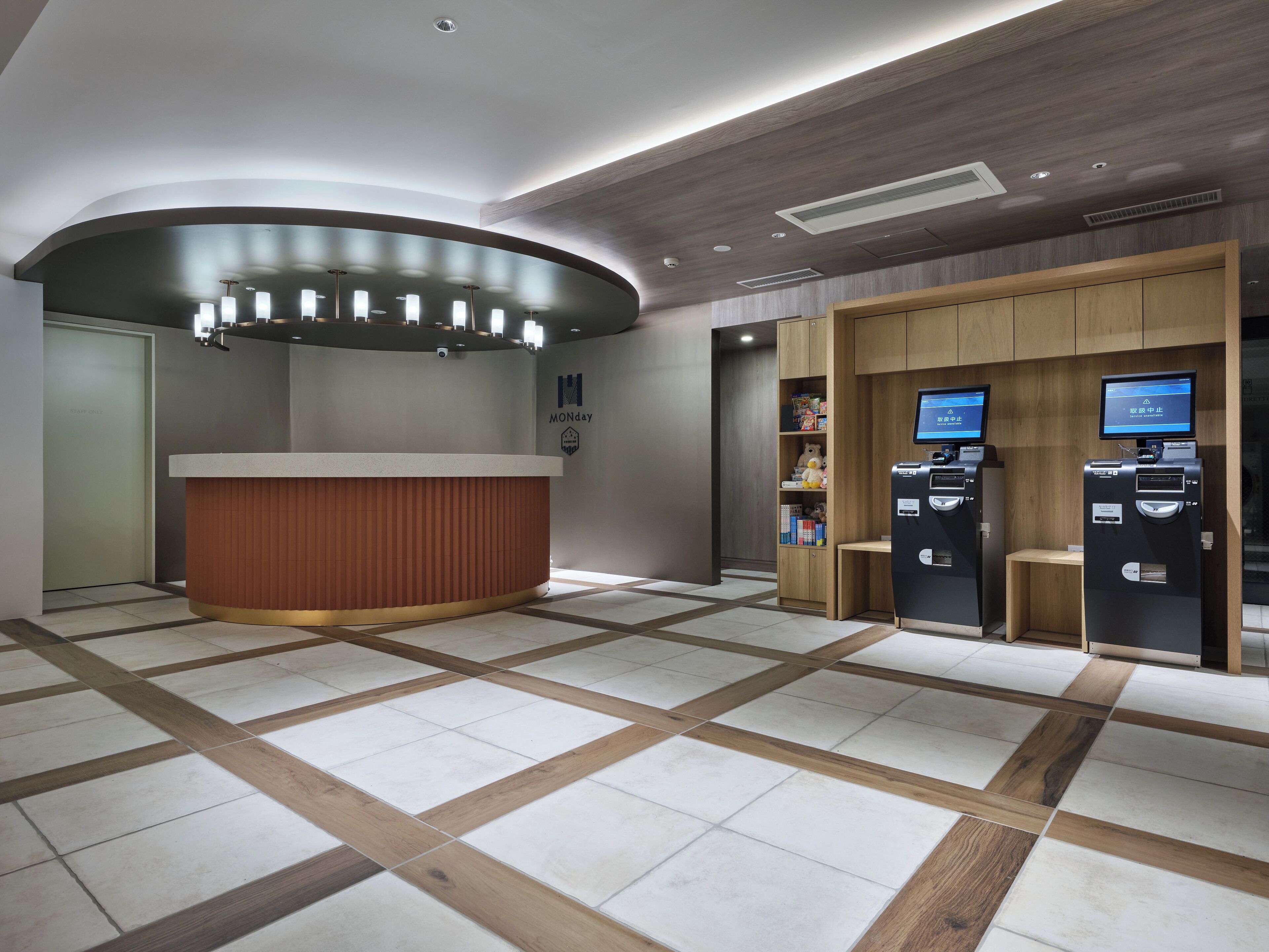 A reception area with a wooden reception desk, a curved ceiling with recessed lighting, a wall-mounted information kiosk, and a tiled floor with a wood grain pattern.