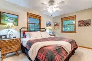 A bedroom with a bed, nightstands, a ceiling fan, and artwork on the walls. - Decks + Lake Access: Scenic North Carolina Retreat (Old Fort)
