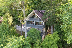 A house surrounded by dense forest, with a large porch and a covered deck. - Decks + Lake Access: Scenic North Carolina Retreat (Old Fort)