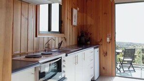 A wooden-paneled kitchen with a built-in oven, a sink, and a window.