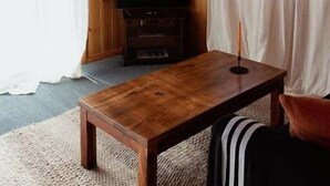 A wooden-paneled room with a wooden table, a television, and curtains.