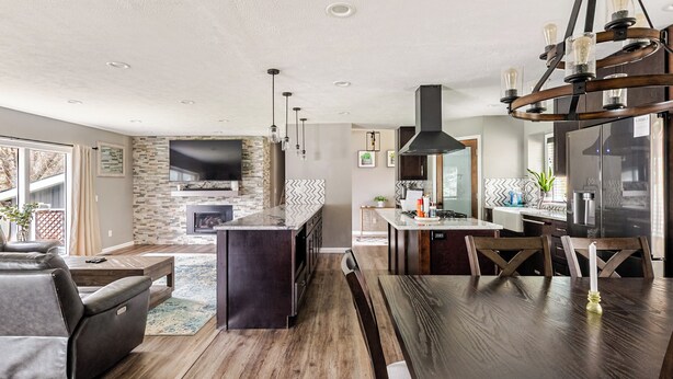 A modern kitchen with a built-in oven, a dining area with a wooden table and chairs, and a living room with a sofa and a TV. - Spacious 5-bedroom house in North Spokane with Hot tub & game room. (Spokane)