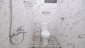 Un baño con inodoro, ducha y perchero para toallas.