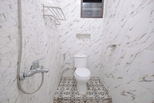 Un baño con inodoro, ducha y perchero para toallas.