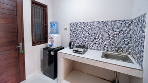 Una cocina compacta con pileta, dispensador de agua y heladera pequeña.