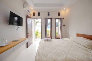 Un dormitorio con cama, televisor montado en la pared, mesita de noche de madera y puerta que da a un balcón.