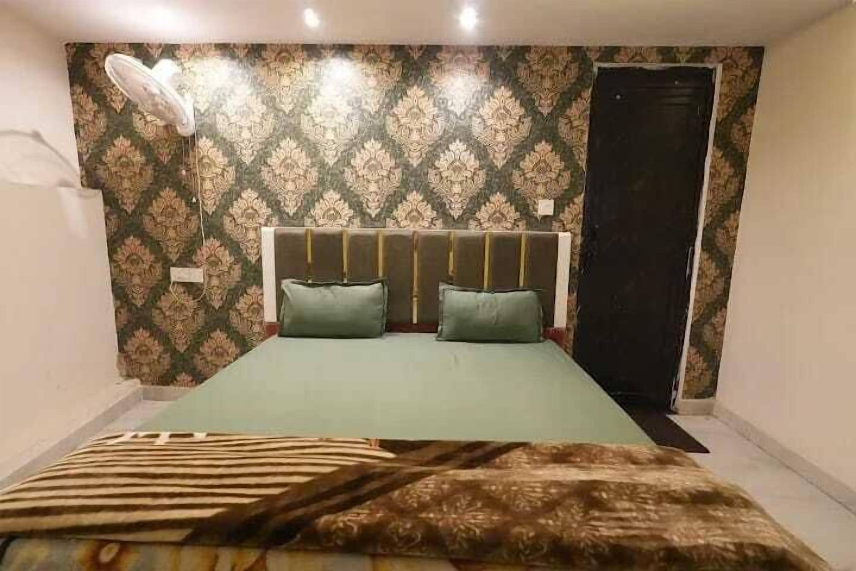 Ein Schlafzimmer mit einem Wandteppich, einem Bett mit zwei Kissen, einer Nachttischlampe und einer Tür.