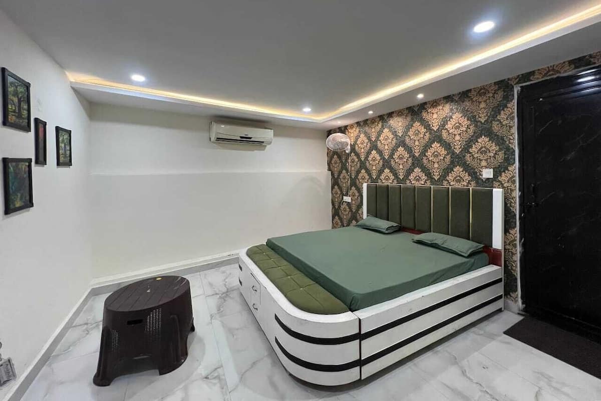 Un dormitorio con cama, aire acondicionado y un taburete.