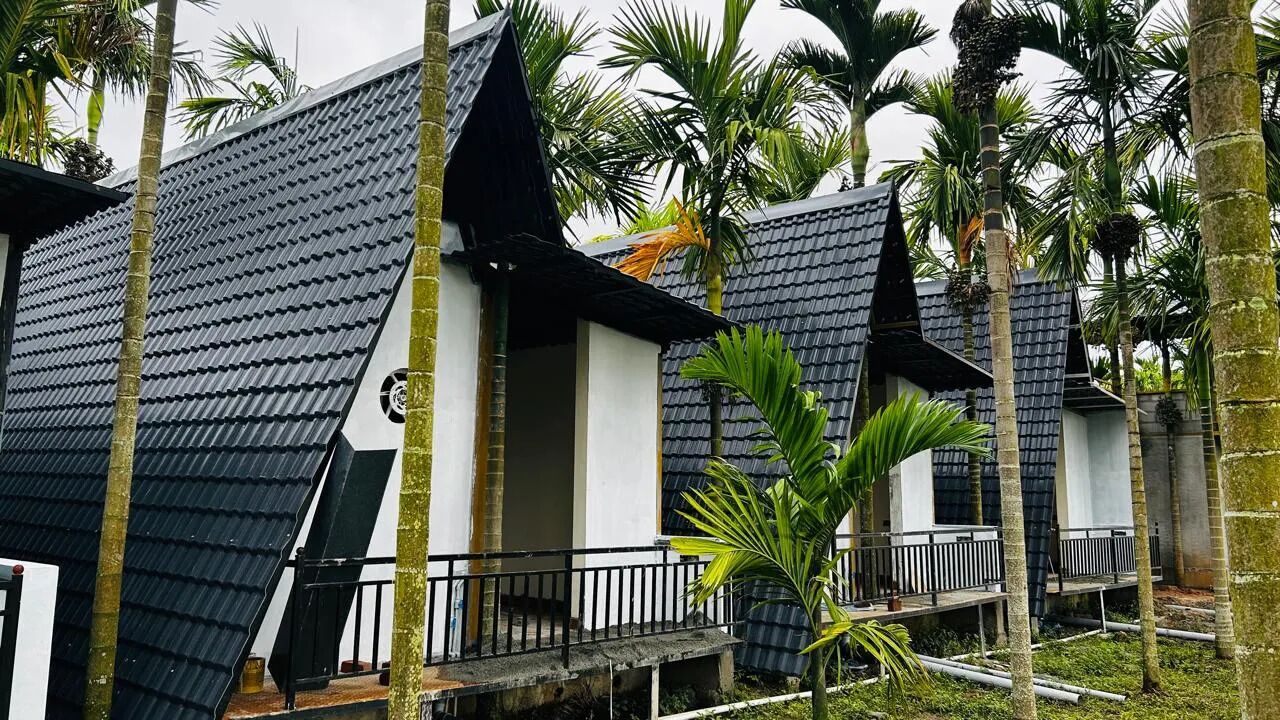 A row of modern, two-story buildings with steeply pitched roofs, surrounded by palm trees.