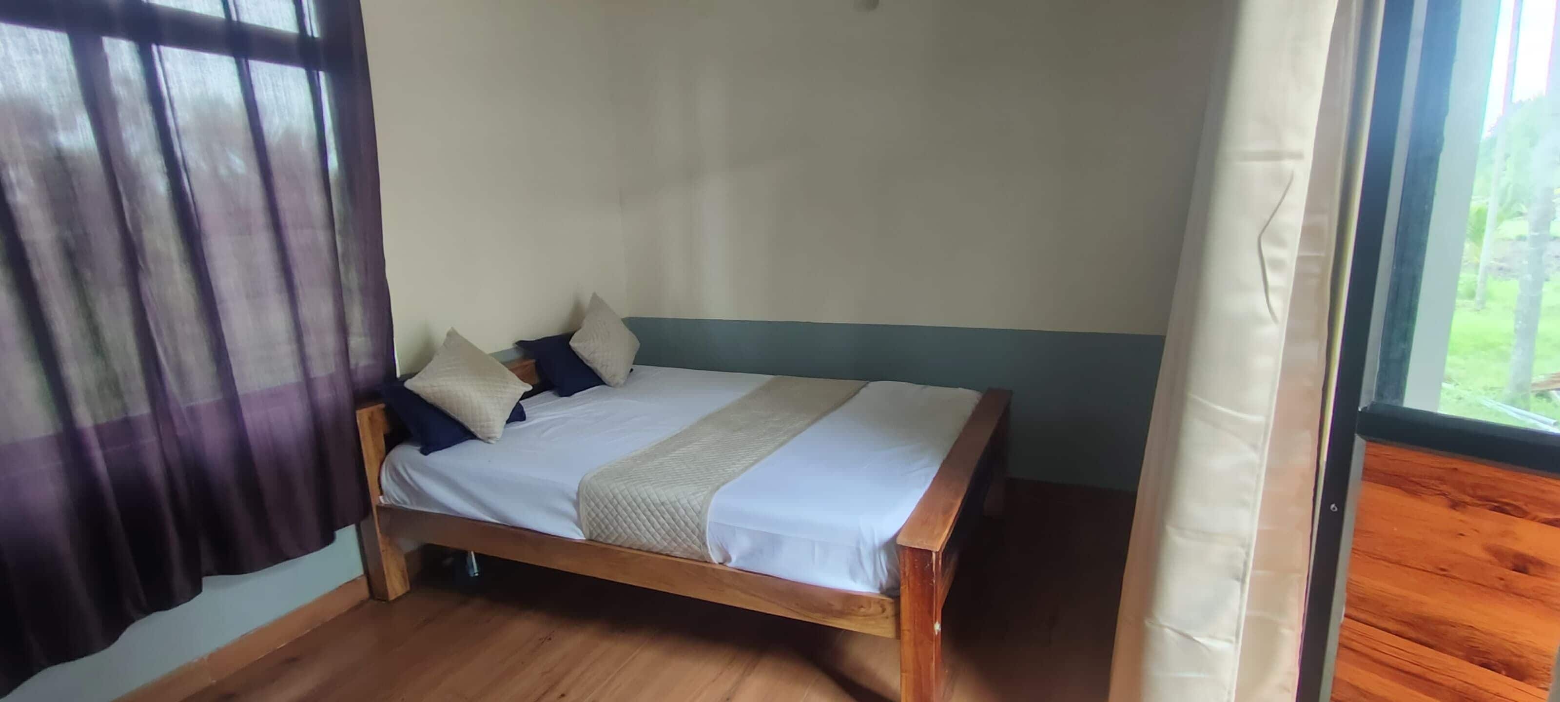 Una cama individual con estructura de madera, ropa de cama blanca y varias almohadas.