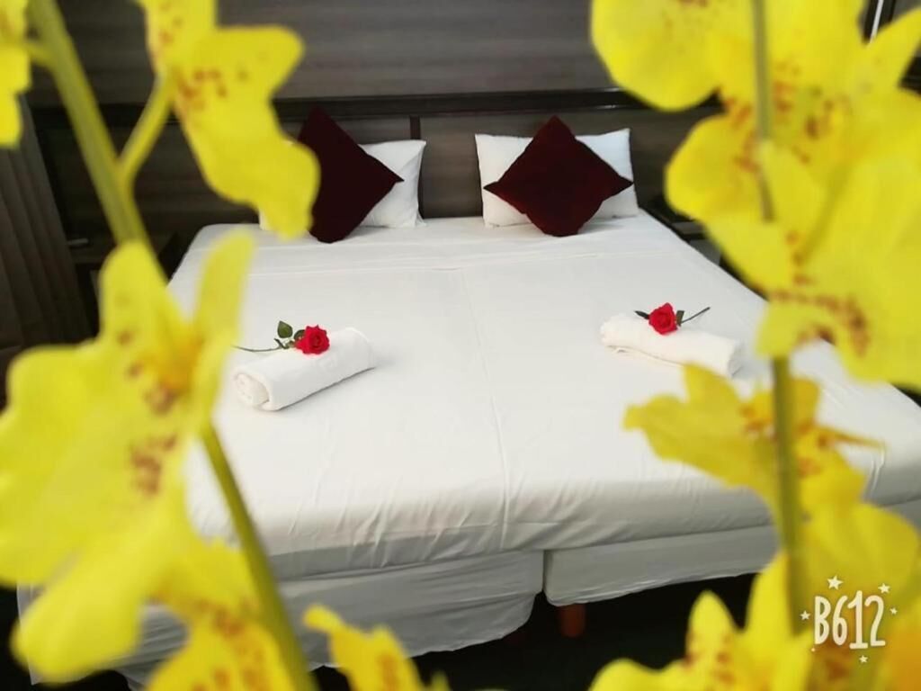 A neatly made bed with white linens and two pillows, one dark and one light.