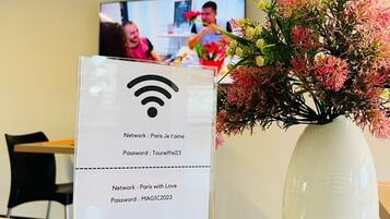 A hotel sign with network and password information, a vase with flowers, and a television in the background.