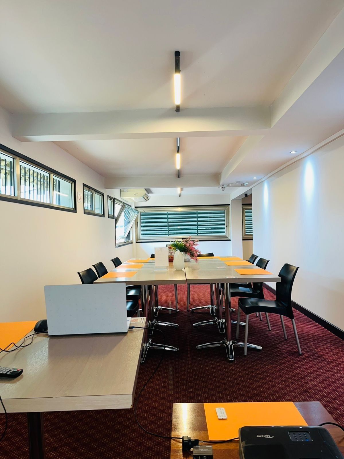 A conference room with a long table, chairs, a laptop, and a projector.