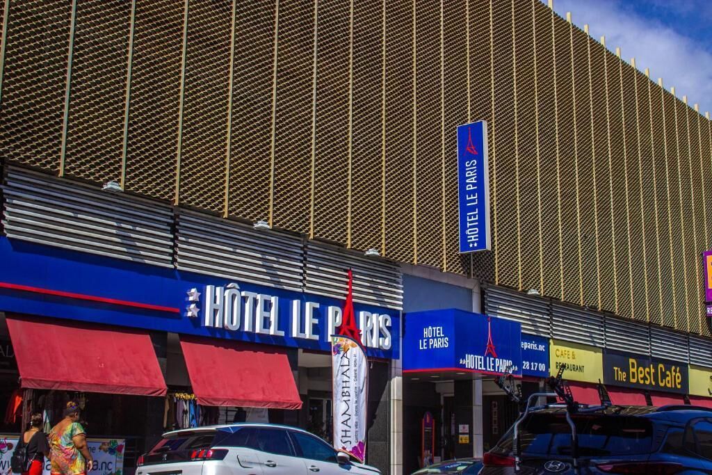 A hotel facade with signage for HOTEL LE PARIS and a prominent red awning.