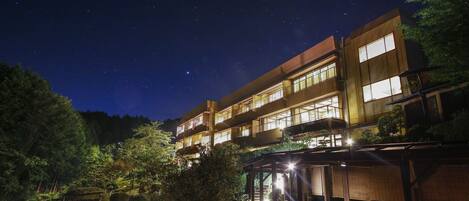 Un edificio de varios pisos con ventanas iluminadas y un espacio exterior cubierto.