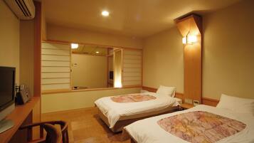 A hotel room with two beds, a desk with a computer, and a TV.