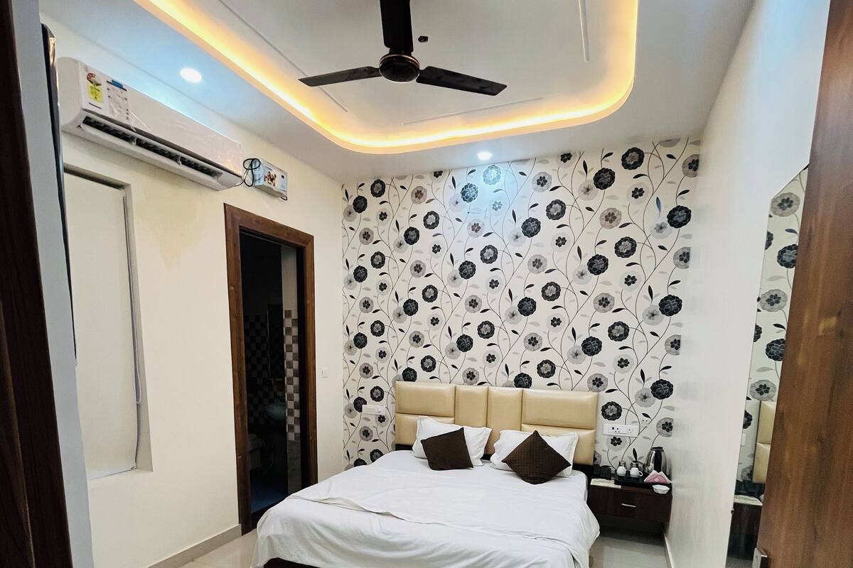 Un dormitorio con cama, ventilador de techo, mesita de noche y pared con estampado floral.