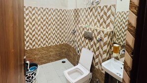 Un baño con inodoro, lavamanos, ducha y ventilador de techo.