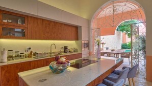 A modern kitchen with wooden cabinets, a central island, and a view of an outdoor patio area. - CASA DE LOS PLATOS, IN THE HEART OF MÉRIDA (Centro)