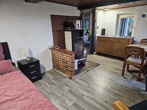 Una habitación acogedora con chimenea de ladrillo, una mesa de comedor de madera y una cama con manta rosa.