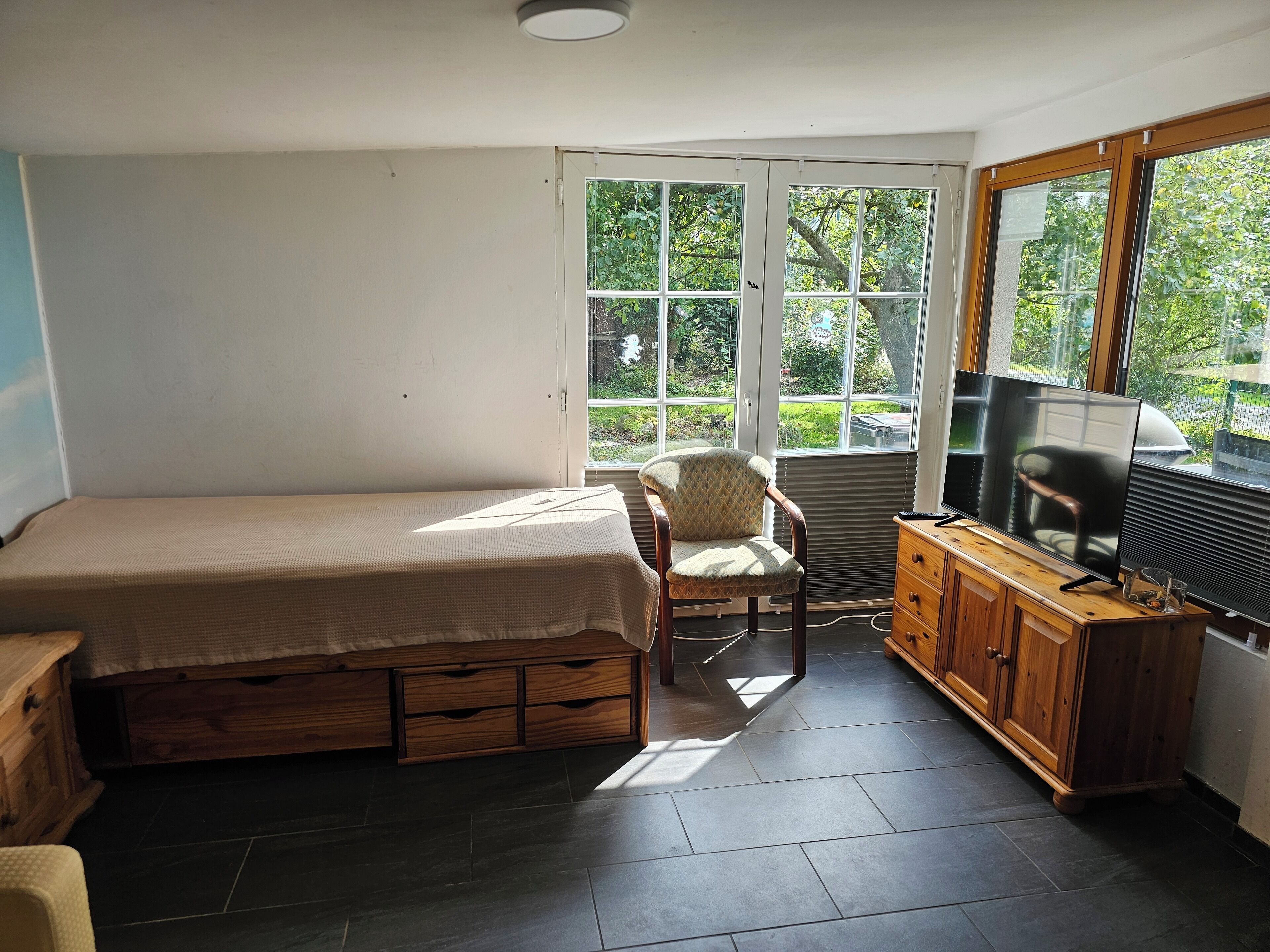 Une chambre à coucher avec un lit, une chaise, un téléviseur et une armoire en bois.