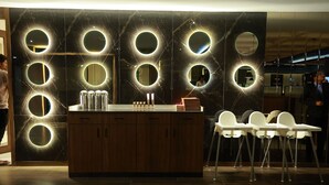 A modern reception area with a marble wall, circular mirrors, and a wooden counter. - Sangam Hotel By Sameeksha By Hospitality (Hyderabad)