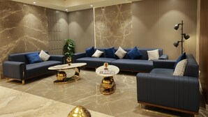 A modern living room with a sectional sofa, two coffee tables, and a decorative plant. - Sangam Hotel By Sameeksha By Hospitality (Hyderabad)