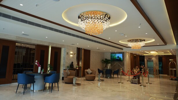 A spacious lobby with a marble floor, a reception desk, seating area, and two chandeliers. - Sangam Hotel By Sameeksha By Hospitality (Hyderabad)
