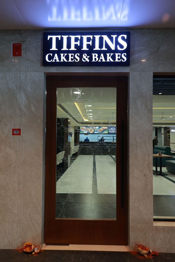 A storefront with a sign reading 'TIFFINS CAKES & BAKES' above a door with a decorative glass panel.