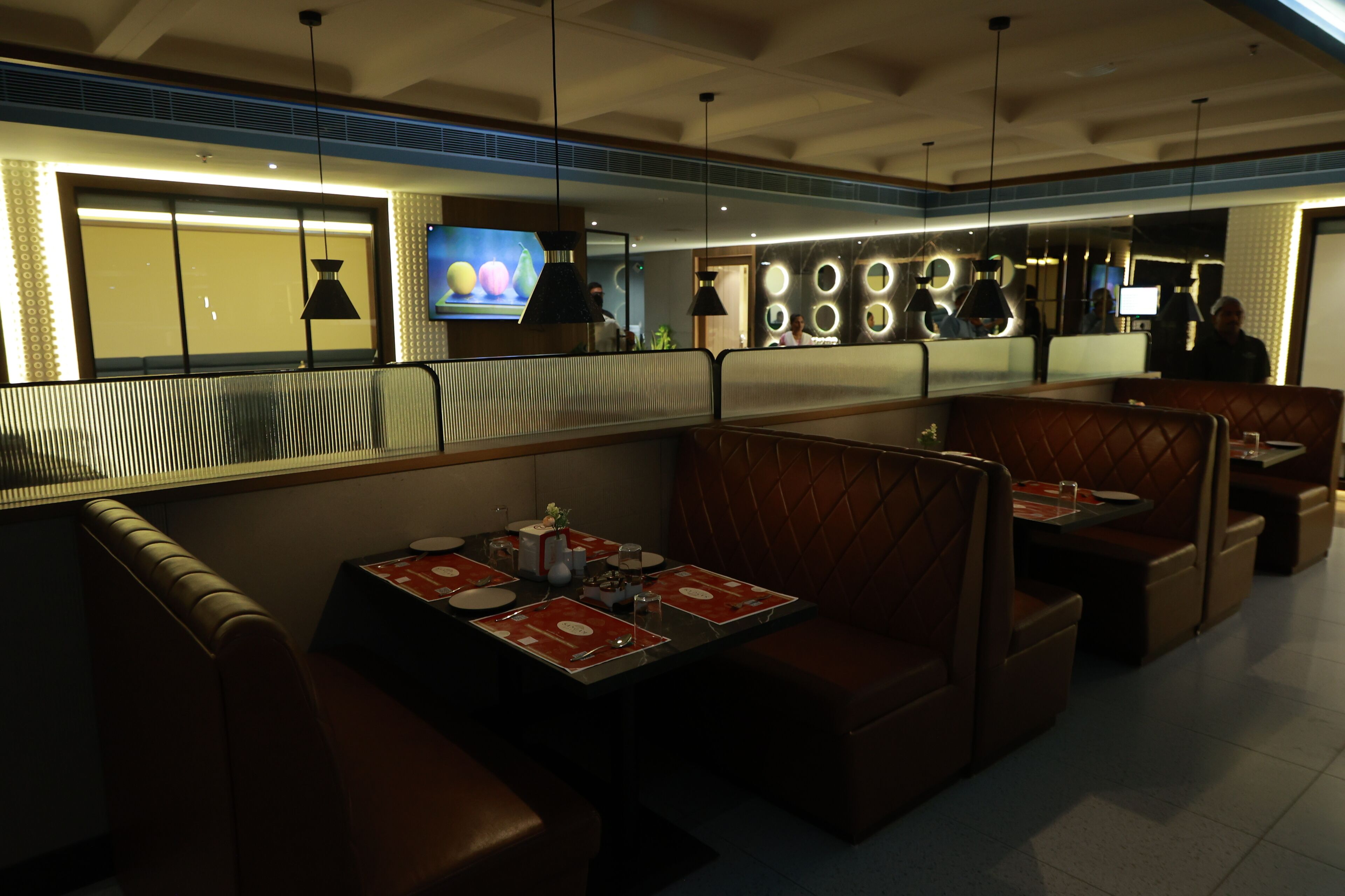 A restaurant with booth seating, a TV screen, and a modern interior design.