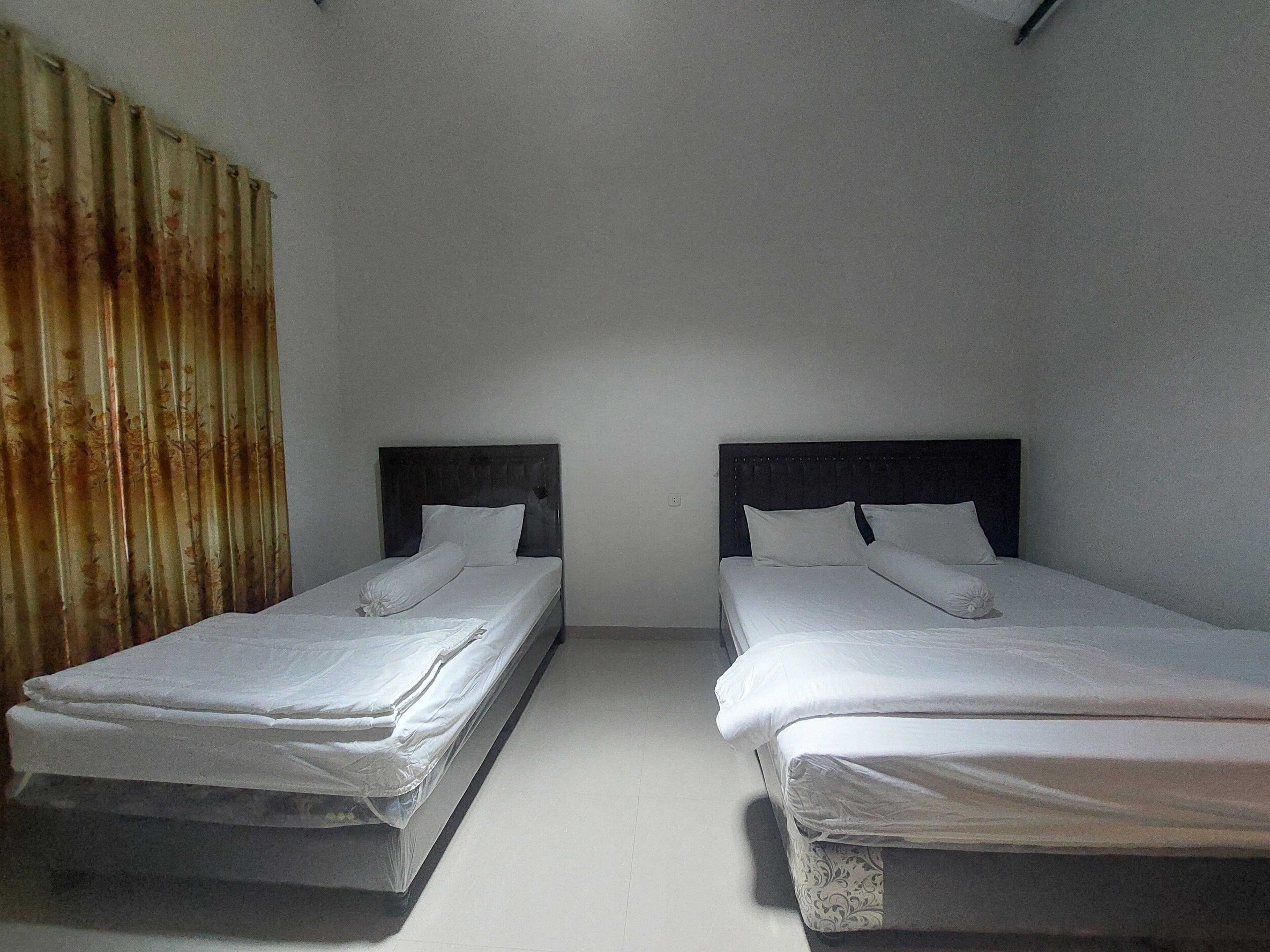 A room with two single beds, each with a wooden headboard and white bedding.