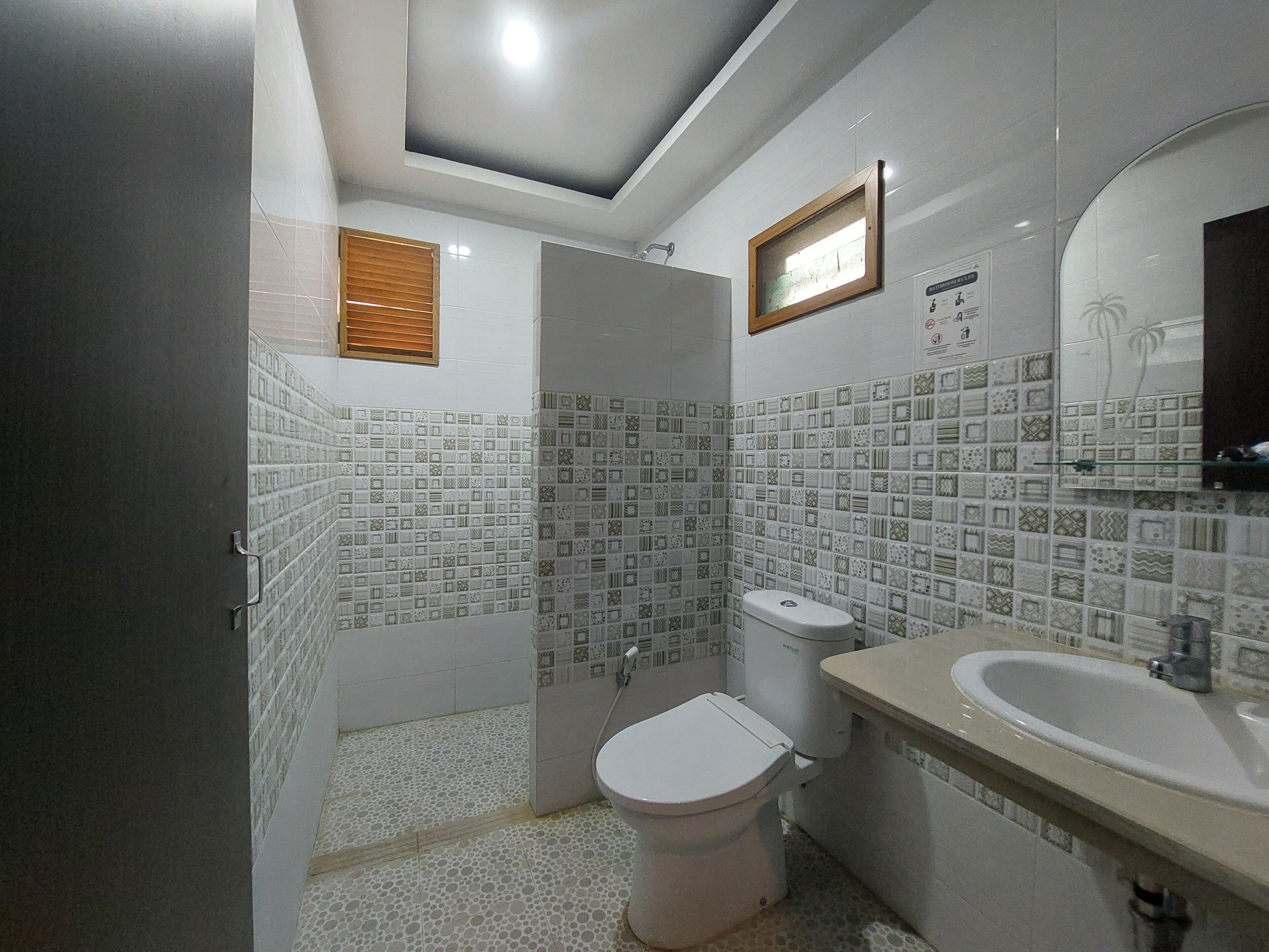 Un baño con baldosas estampadas, un inodoro, un lavabo y un espejo.