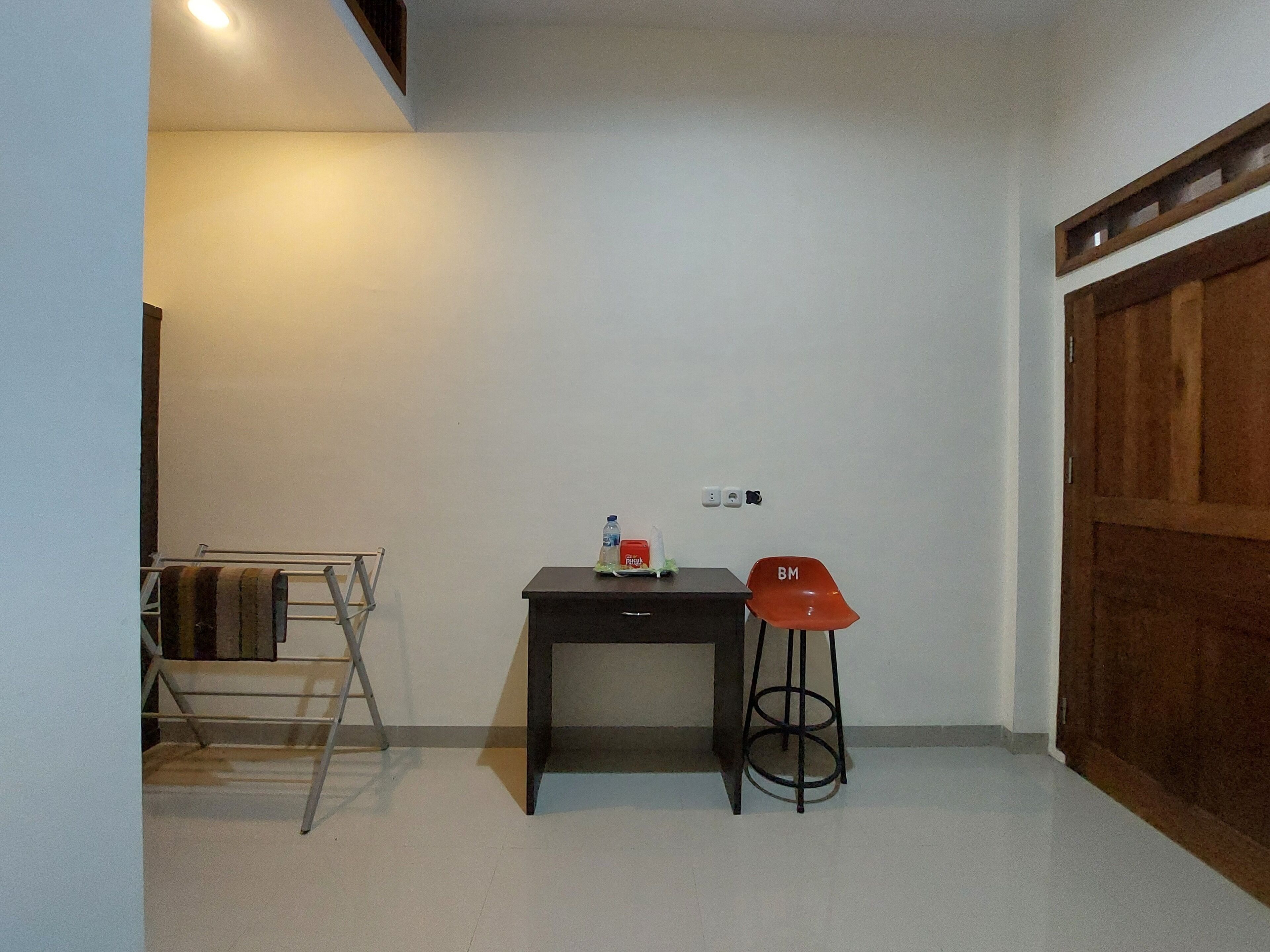 A small, clean room with a desk, a chair, and a wooden wardrobe.