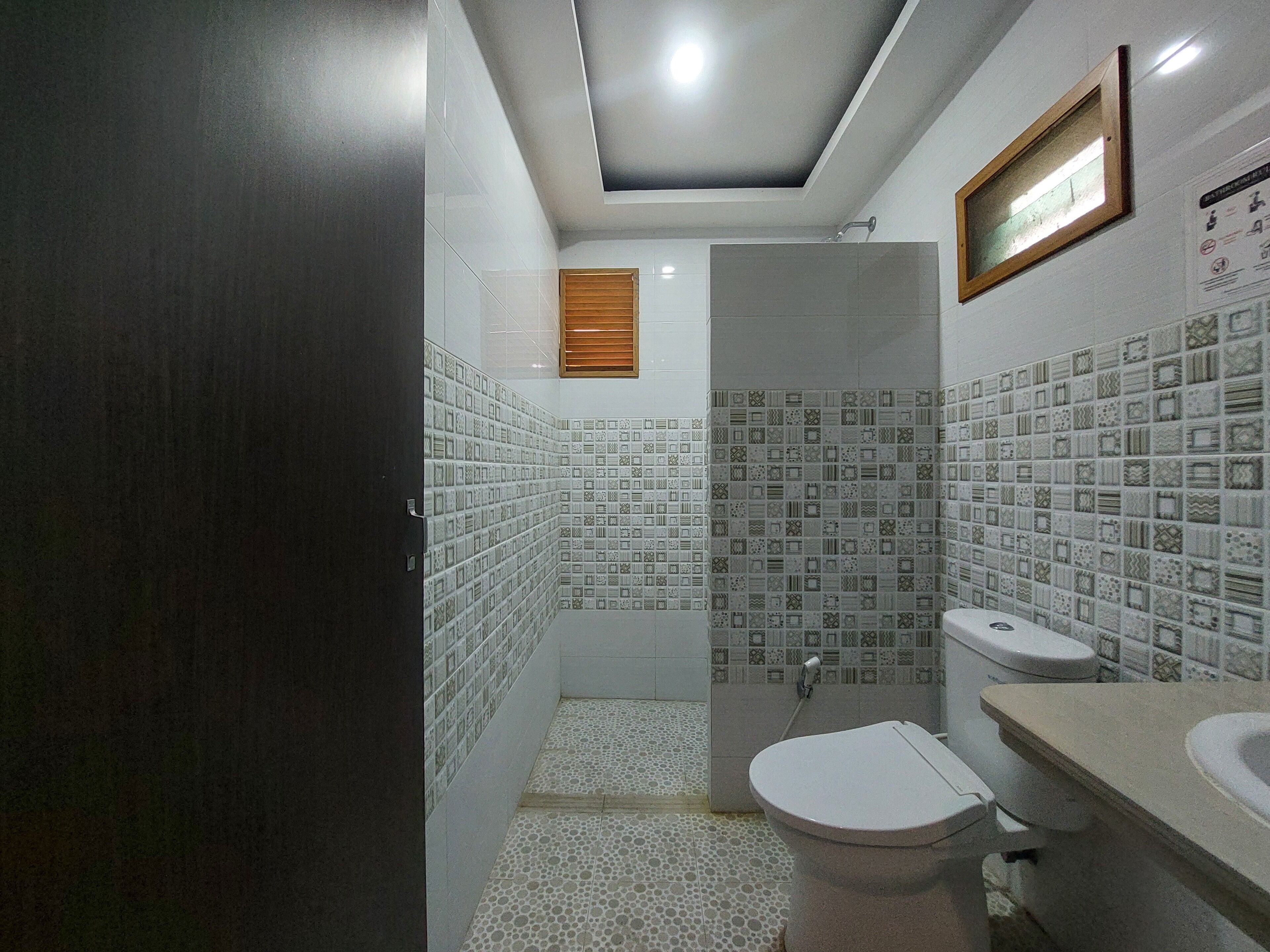 A bathroom with patterned tiles, a toilet, a sink, and a shower.