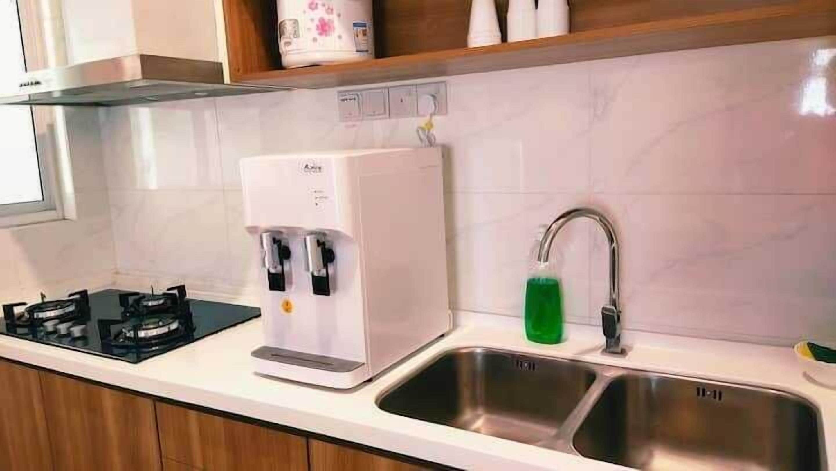 A kitchen with a built-in water dispenser, a stainless steel sink, and a gas stove.