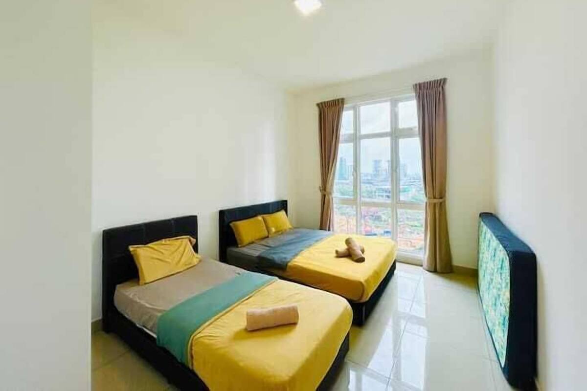 A hotel room with two beds, a large window with curtains, and a view of the city.