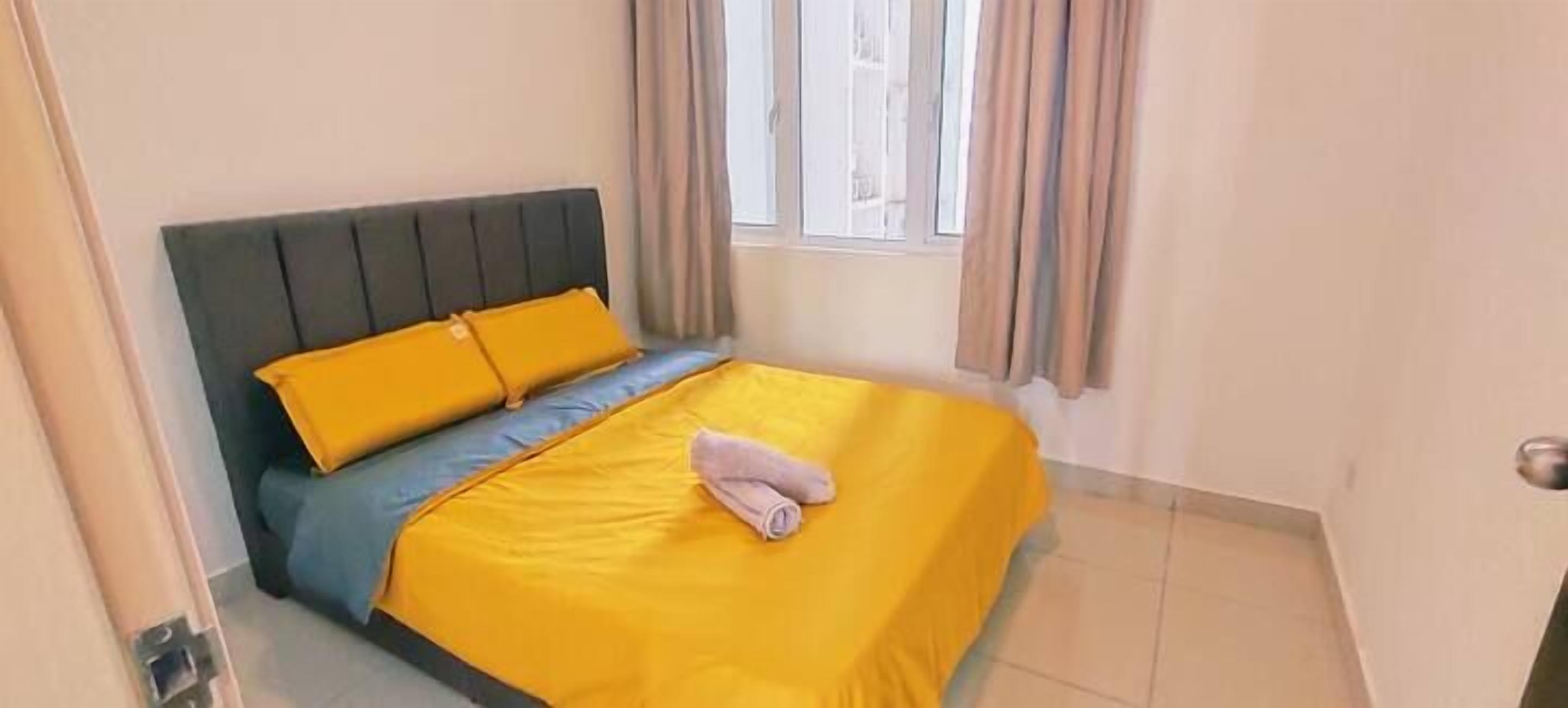 A bed with a grey headboard and yellow bedding, a window with curtains, and a tiled floor.
