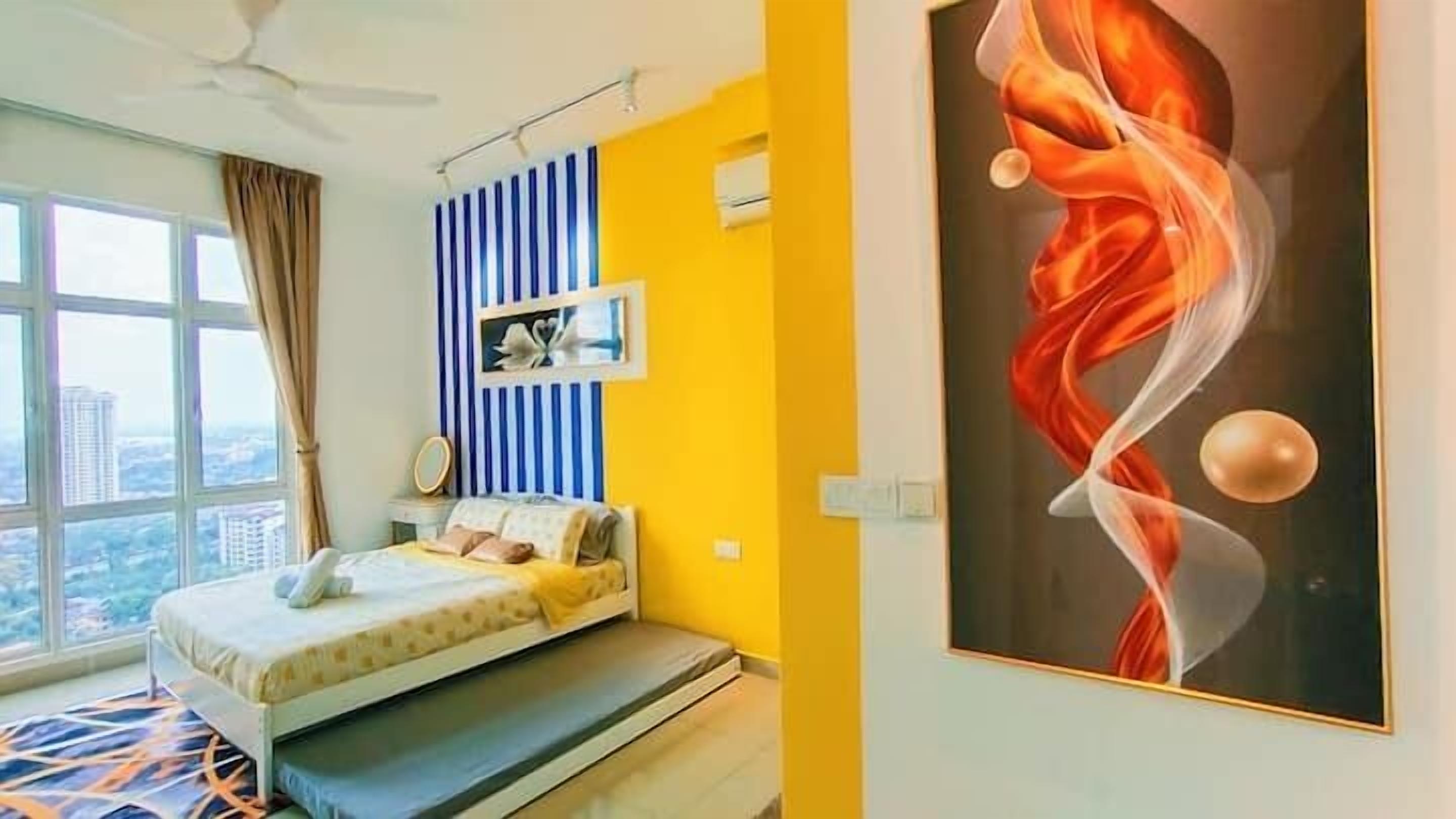 A bedroom with a bed, a window with a view of buildings, a ceiling fan, and a wall with a striped pattern and a picture.